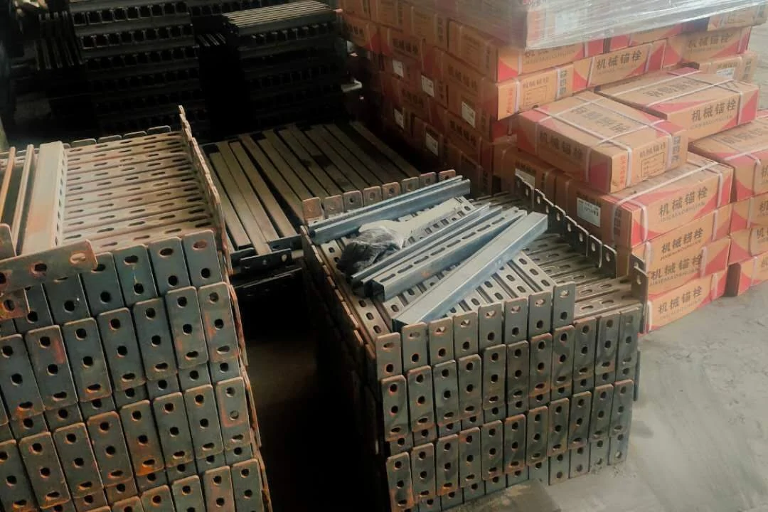 Stacks of galvanised perforated brackets and painted slotted profiles in the factory