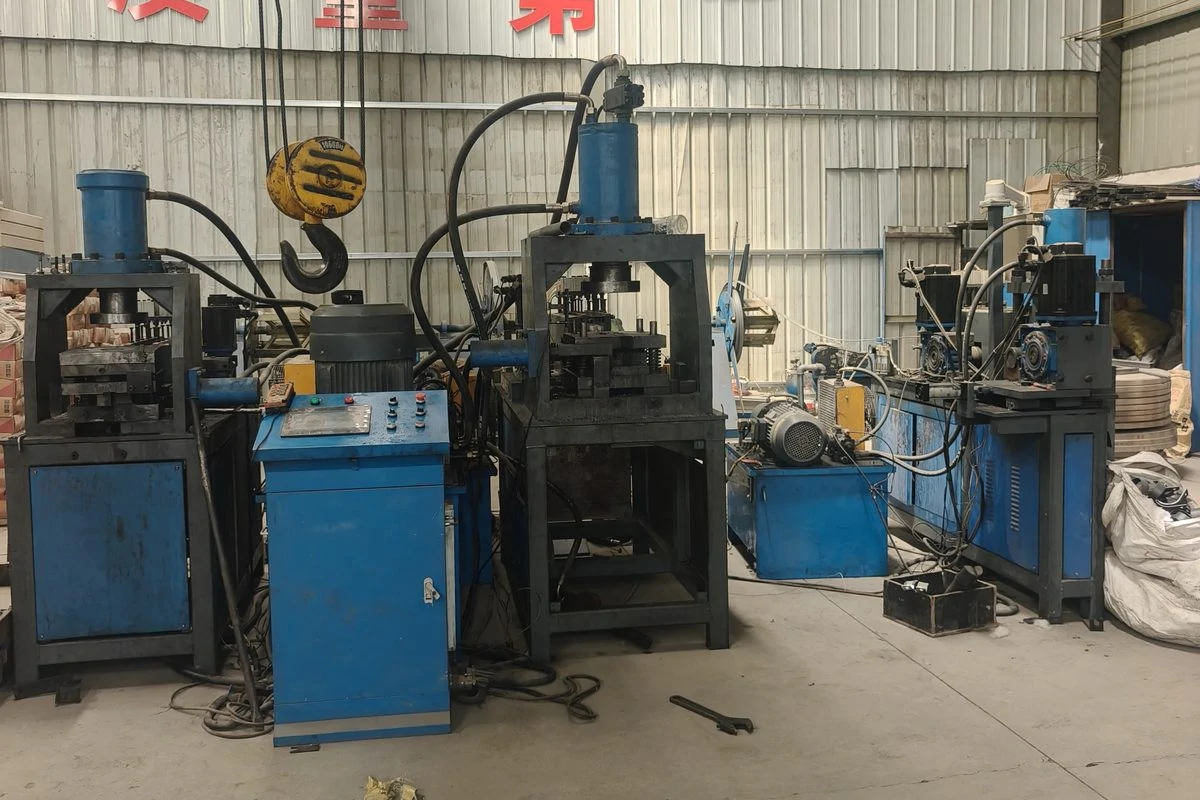 Three blue-framed hydraulic press stations in a workshop bay