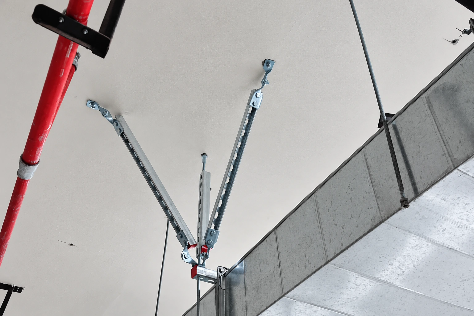 Seismic brace with two diagonal slotted struts installed on a rectangular galvanised air duct