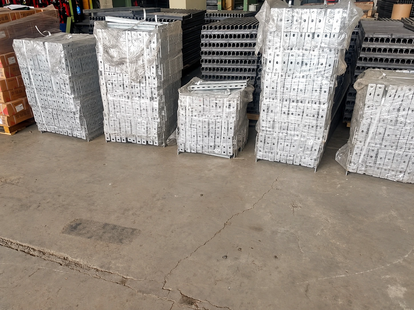 Shrink-wrapped pallets of galvanised perforated steel brackets lined up in the factory