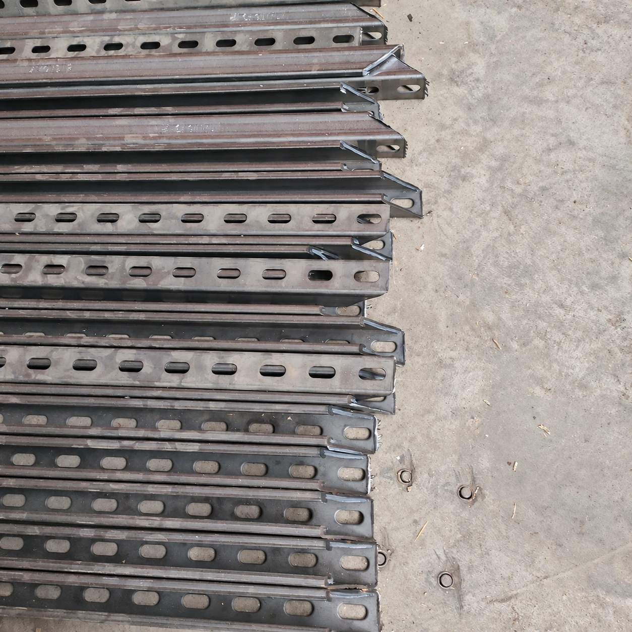 Rows of perforated galvanised channel profiles laid out on the factory floor