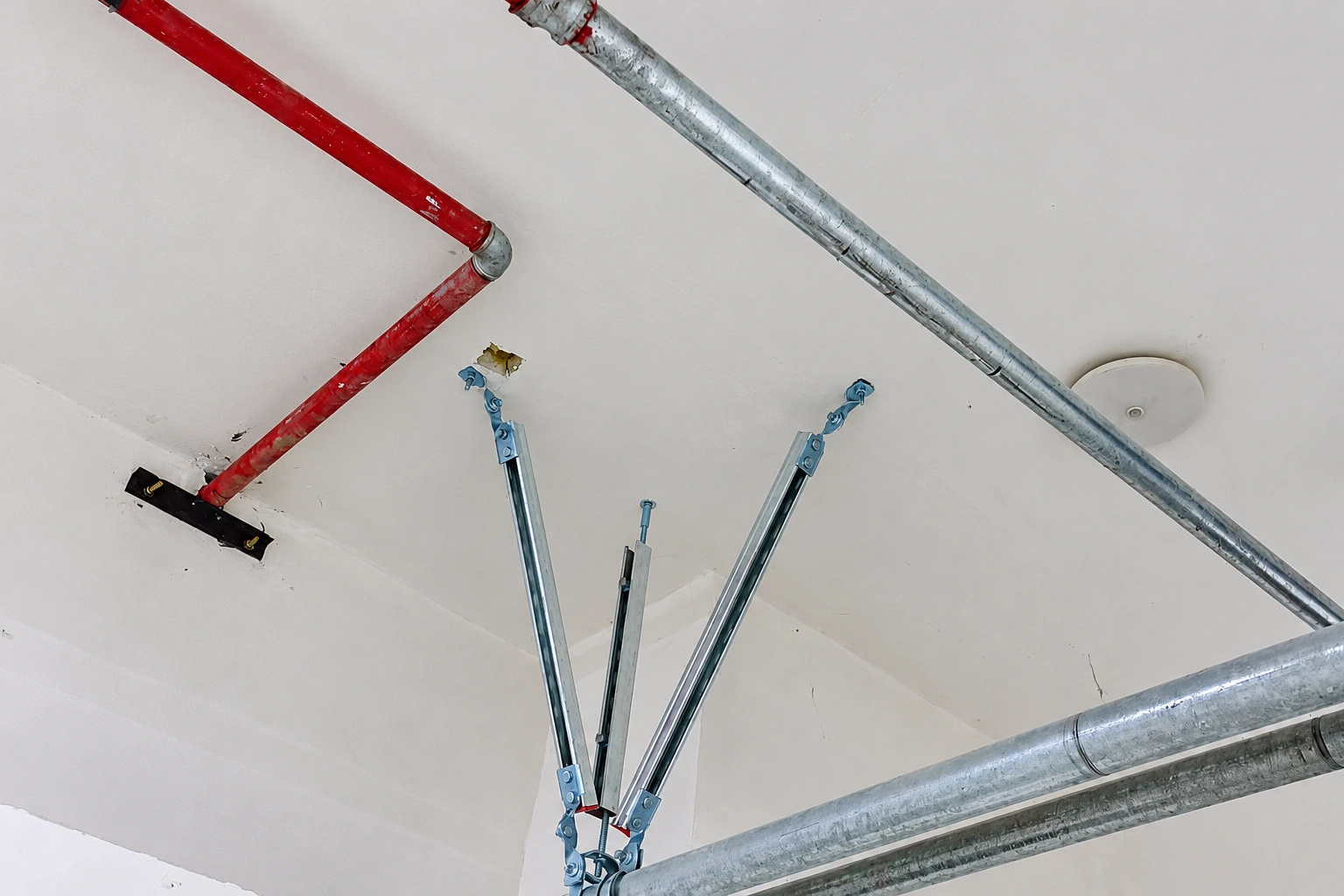 Two diagonal brace struts bolted to a pipe clamp on a galvanised sprinkler pipe