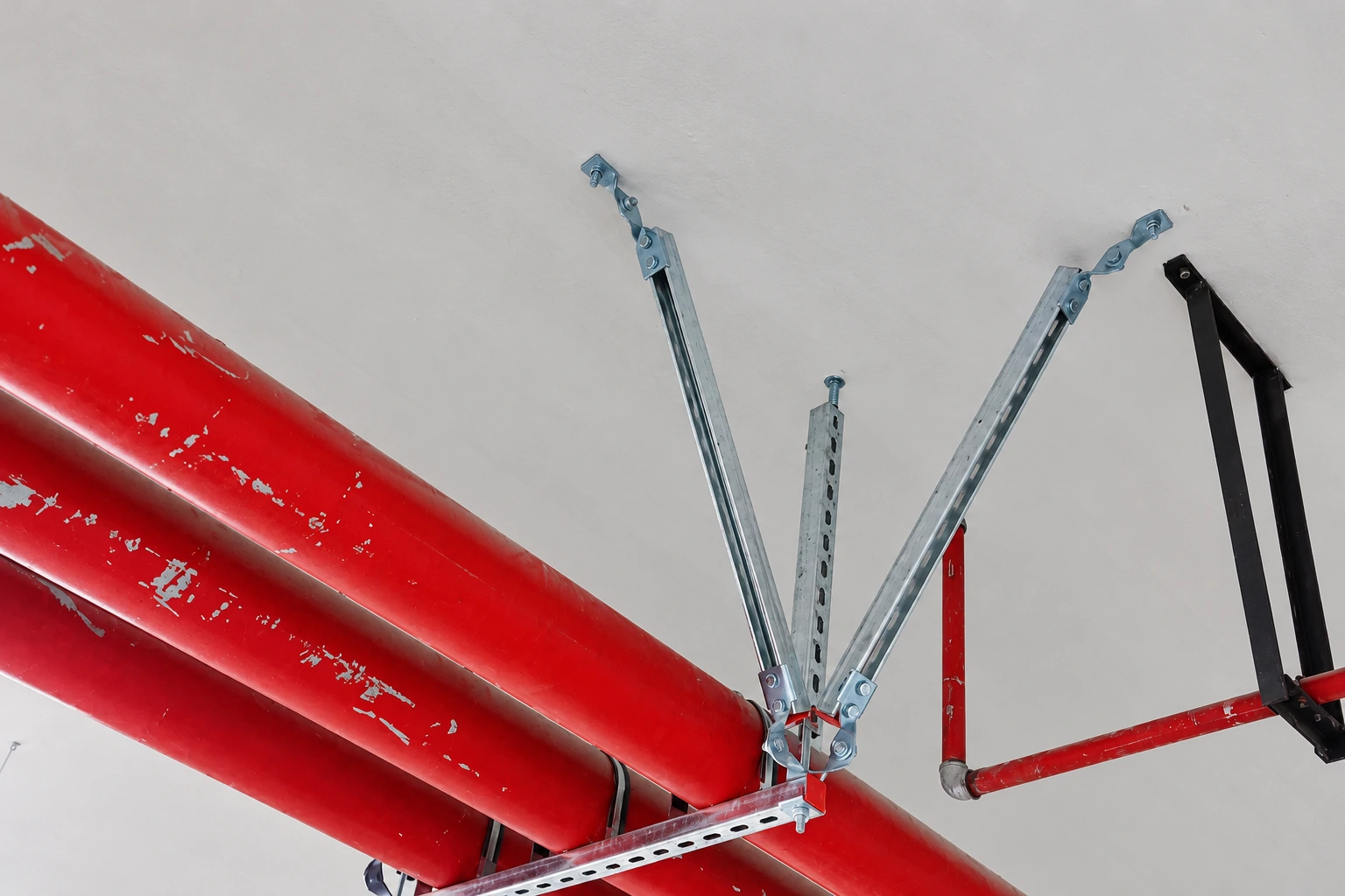 Diagonal seismic brace struts anchored to the ceiling and clamped to two red fire pipes