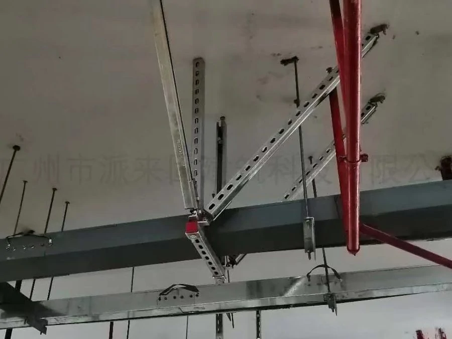 Perforated strut channel braces clamped to a steel beam and supporting ceiling-mounted services
