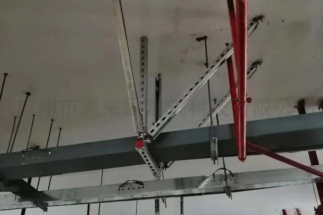 Perforated strut channel braces clamped to a steel beam and supporting ceiling-mounted services