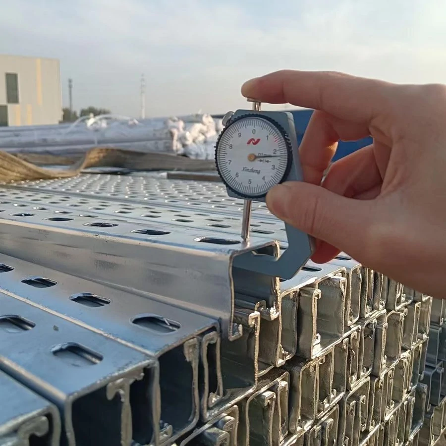Hand holding a dial gauge against the edge of a galvanised slotted strut channel