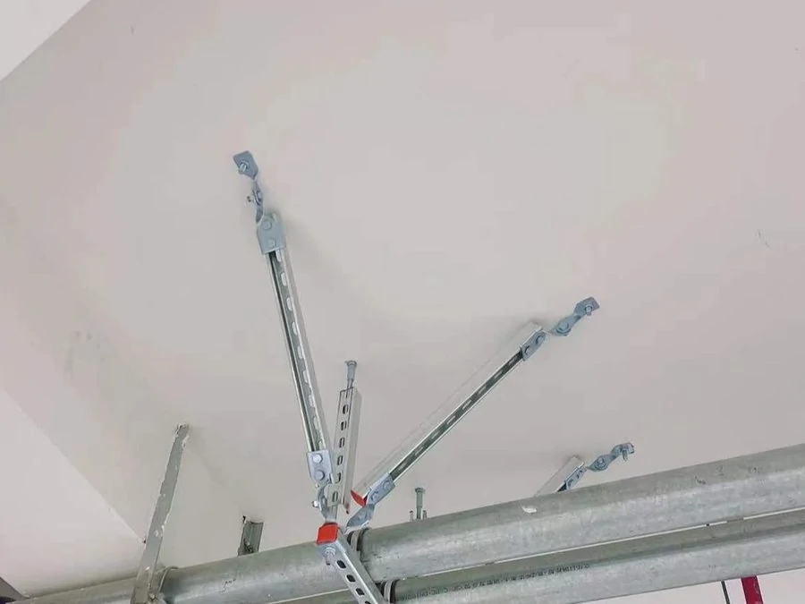 Seismic bracing fixed to two parallel galvanised pipes below a white ceiling