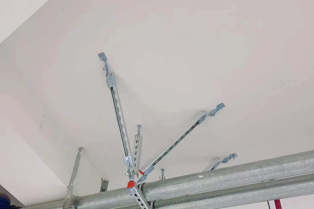 Seismic bracing fixed to two parallel galvanised pipes below a white ceiling